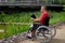 Disabled man in wheelchair having fun while resting using a tablet computer at park, concept of technological and occupational