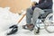 Disabled man on wheelchair with snow showel in the yard