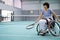 Disabled mature woman on wheelchair playing tennis on tennis court