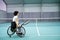 Disabled mature woman on wheelchair playing tennis on tennis court.