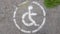 Disabled parking symbol. Disabled bay marked with a person in a wheelchair sign on gray asphalt in a large parking lot close up.