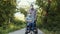 Disabled person woman in wheelchair with her man stand on the path in park wearing masks to protect against the virus