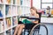 Disabled school girl reading book in library