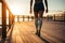 disabled sportswoman with a prosthetic leg walks outdoors on a plank floor along the sea promenade at sunset