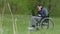 Disabled thinks problems man wheelchair with laptop in wheelchair working on nature green background