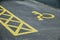 Disabled or wheelchair car parking space marked out in yellow paint on black tarmac