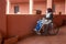 Disabled woman alone in a wheelchair with a protective mask looking out from the balcony of the house staying home for the quarant