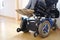 A disabled woman sitting in a blue electric wheelchair indoors