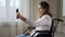 Disabled woman in wheelchair talks on videocall at home