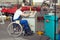 Disabled worker in wheelchair in factory and colleague