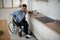 Disabled Young Man in Wheelchair Preparing Food In Kitchen.