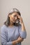 Disappointed Adult Woman of Mongolian Nationality with Gray Hair on a Gray Background.