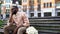 Disappointed male sitting lonely on city bench with flower bouquet, failed date