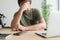 Disappointed telecommuter at home office desk covering face with his hand