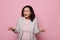 Disappointed woman gesturing with hands, asking what looking at camera, expressing misunderstanding on pink background