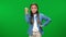 Disapproving shocked teen girl gesturing fist up and smiling standing on green screen background. Medium shot front view