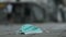 Discarded medical face mask lies on the sidewalk, peoples walk and cars drive on the background in soft focus. Face masks pollutin