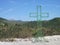 Discarded wire framed cross with hills and mountains in the background.