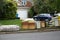 Discarded wooden furniture and an old bed lined up by the curb near a street waiting for trash pickup