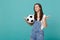 Disconcerted displeased young woman football fan support favorite team with soccer ball spreading hands isolated on blue