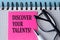 DISCOVER YOUR TALENTS! - words on a pink piece of paper on a white notebook with glasses and pen