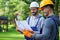 Discussing ideas. Portrait of two positive builders standing outdoors with an open blueprint discussing the half