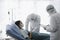 Disease treatment room for infected patient, infected patient woman lying in bed with doctor wearing protective clothing in