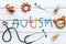 Diseases. Infantile autism. Word with colored letters near toys, stethoscope, pills on white wooden background top view