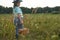 A disgruntled child with a full basket of mushrooms in his hand in the grass in a picturesque forest clearing. Copy space.