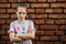 Disgruntled girl frowns, stands upset against a brick wall