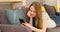 Disgruntled upset girl scrolls through the news feed on Internet. Woman lies on the couch with smartphone