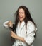 Disgruntled woman combing her tangled hair on white background, hair care and hair problem concept