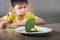 Disgusted child refusing to eat healthy green broccoli feeling upset in kid nutrition education on healthy fresh food and young