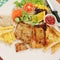 A dish of fired pork and chicken steak with bread , French fried and salad