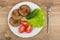 Dish with fried cutlets, lettuce, tomato, cucumbers, fork on tab