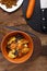 A dish of Jewish cuisine sweet tsimes with vegetarian dates carrots in a plate on a round stand on a wooden background next to