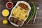 Dish with pasta, cutlet, beans, green onion and olives, mayonnaise, ketchup, pepper, fork on table. Top view