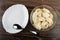 Dish, spoon, dumplings with butter in transparent bowl on wooden table. Top view