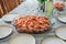 A dish of unpeeled shrimp on a dinner table with plates. Seafood diner. Boiled shrimps.