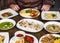 Dishes with different foodman hands with a knife and fork at table with many different food