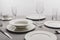 Dishware and transparent glasses on tablecloth on grey background