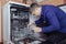 Dishwasher repair. A service center representative diagnoses and repairs a dishwashing machine at home. Specialist in working with