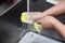 Dishwasher in uniform washes griddle with foam and sponge under the tap water