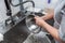 Dishwasher in uniform washes griddle with foam and sponge under the tap water