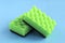 Dishwashing sponge. two green sponges for washing dishes and other surfaces on a blue background. cleaning concept