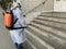 Disinfecting by spray from Corona virus of residential building entrance by worker in special uniform, epidemic