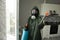 Disinfection of coronavirus in the apartment. People in protective suits make professional cleaning of the room from viruses and