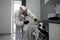 Disinfection of coronavirus in the apartment. People in protective suits make professional cleaning of the room from viruses and