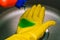 Disinfection of the home and work space. Prevention of COVID-19. Close-up of a gloved hand and an orange bottle of disinfectant.