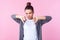 Dislike! Portrait of dissatisfied brunette teenage girl making thumbs down gesture, expressing discontent. pink background